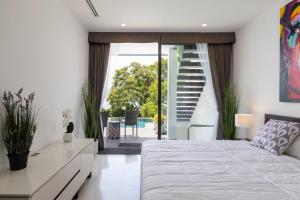 a bedroom with a large white bed and a staircase at Atika Villa Patong in Patong Beach