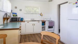eine Küche mit weißen Schränken und einer Arbeitsplatte in der Unterkunft Lowset, pet friendly cottage - Sunset Ave, Bongaree in Bellara