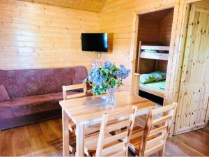 Habitación de madera con mesa y florero en Domki Letniskowe WIKTORIA en Jezierzany