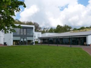 a large white building with a green field in front at Haus am See - Gochness in Kessel