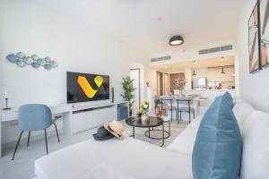 a living room with a white couch and a tv at Vogue - 1 Residence - Dubai Frame & Park Views Near Metro in Dubai