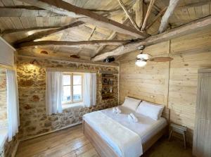 ein Schlafzimmer mit einem Bett in einem Holzzimmer in der Unterkunft Agios Ioannis Stone Cottage with Private Heated Pool & Hydro-massage in Áyios Ioánnis