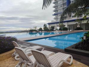 a swimming pool with chairs next to a building at Fatih Amani Guesthouse with Playstation PS3 in Kajang