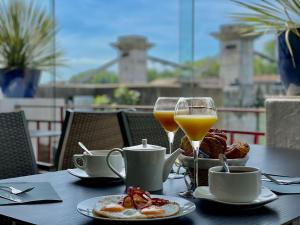a table with breakfast food and two glasses of orange juice at Hôtel Les Deux Coteaux in Tain-lʼHermitage