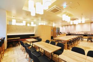 a restaurant with wooden tables and chairs and chandeliers at hotel MONday Asakusa in Tokyo