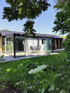 een huis met glazen deuren en een tuin bij Traumhaftes Chalet am Veluwemeer, Bad Hoophuizen in Hulshorst