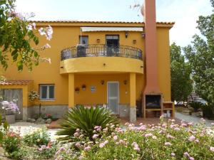 a yellow house with a balcony and flowers at Casita Melanie in Alhaurín el Grande