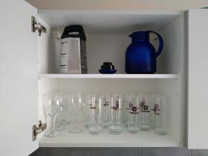 a cupboard filled with wine glasses and a blue pitcher at Ferienhaus Opolka in Balgstädt
