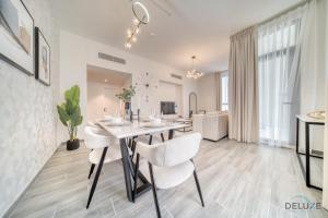 uma sala de jantar com uma mesa e cadeiras brancas em Exquisite 2BR with Assistant Room at Mesk 1 Midtown Dubai Production City by Deluxe Holiday Homes em Dubai