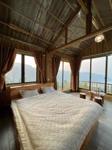 um quarto com uma cama grande num quarto com janelas em Homstay Gốc Vải em Dan Mey