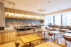 東京的住宿－hotel MONday Akihabara Asakusabashi，餐厅设有木桌、椅子和柜台
