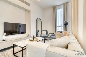 a living room with a white couch and a tv at Exquisite 2BR with Assistant Room at Mesk 1 Midtown Dubai Production City by Deluxe Holiday Homes in Dubai
