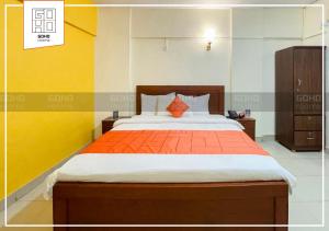 um quarto com uma cama grande e um cobertor laranja em GOHO Rooms 10th Commercial em Carachi