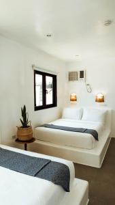 Duas camas num quarto com paredes brancas em Hostel Bajala Siargao em General Luna