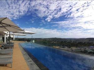 a large swimming pool with chairs and an umbrella at Menlyn Maine Apartments in Pretoria