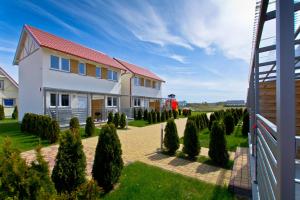 a house with a yard with trees and bushes at Słoneczna Kajuta - Apartmenty/Domki in Dębki