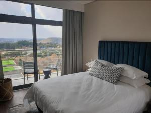 a bedroom with a bed and a large window at Menlyn Maine Apartments in Pretoria