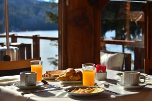 a table with breakfast food and orange juice on it at Dos Bahias Lake Resort in Villa La Angostura