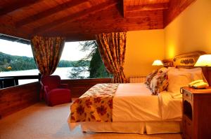 a bedroom with a bed and a large window at Dos Bahias Lake Resort in Villa La Angostura
