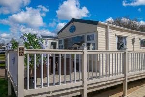 a white fence in front of a house with a clock at Tattershall Lakes Private Hot Tub Lodge - sleeps 6 in Lincoln