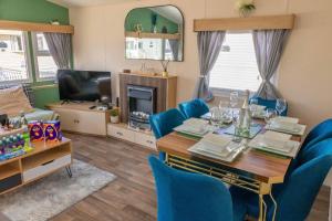 a dining room with a table and blue chairs at Tattershall Lakes Private Hot Tub Lodge - sleeps 6 in Lincoln
