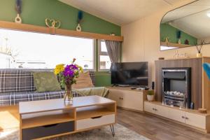 a living room with a couch and a fireplace at Tattershall Lakes Private Hot Tub Lodge - sleeps 6 in Lincoln