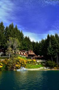 une grande maison sur une colline à côté d'un lac dans l'établissement Dos Bahias Lake Resort, à Villa La Angostura
