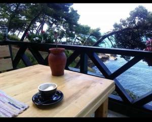 a vase sitting on a wooden table with a cup at Rooms Jancic in Ulcinj