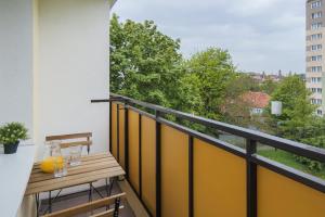 einen Balkon mit einem Holztisch mit Gläsern darauf in der Unterkunft Cosy Apartment for 5 Guests Gdańsk Wrzeszcz by Renters in Danzig