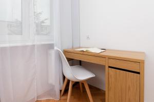 einen Schreibtisch mit einem weißen Stuhl neben einem Fenster in der Unterkunft Cosy Apartment for 5 Guests Gdańsk Wrzeszcz by Renters in Danzig