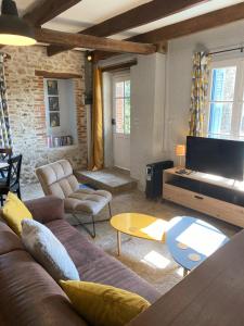 - un salon avec un canapé et une télévision dans l'établissement Maison de Montgibaud, à Montgibaud