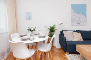 ein Esszimmer mit einem weißen Tisch und einem blauen Sofa in der Unterkunft Cosy Apartment for 5 Guests Gdańsk Wrzeszcz by Renters in Danzig