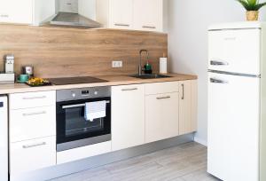 a kitchen with white cabinets and a sink and a refrigerator at Under The Pine in Engure +15 photos