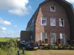 een zwarte auto geparkeerd voor een bakstenen huis bij Oomes Huus - Sleep by Hästens, Wake with Coffee in Den Hoorn