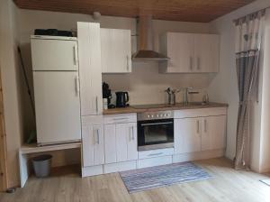 cocina con armarios blancos y nevera en Ferienwohnung Wiesenblick, en Oberharmersbach