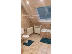 baño con aseo, bañera y ventana en Ferienwohnung Wiesenblick, en Oberharmersbach