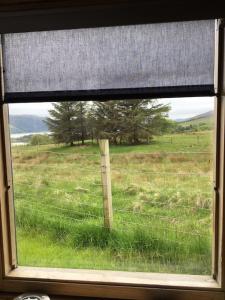a window with a view of a field with a fence at sterlochy dome in Lochcarron