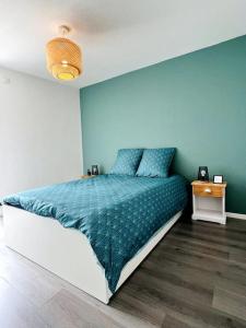 een slaapkamer met een bed en een blauwe muur bij Zen et détente in Roanne