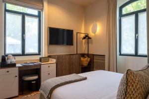a bedroom with a bed and a tv and windows at Casa da Marechal - Boutique Hotel by Oporto Collection - Adults Only in Porto