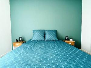 een slaapkamer met een blauw bed en 2 nachtkastjes bij Zen et détente in Roanne