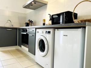 a kitchen with a washing machine and a microwave at Zen et détente in Roanne +5 photos