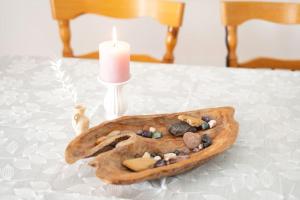 a candle sitting on a table with a wooden tray with rocks at Butterfly Cottage by the Creek in Tržič