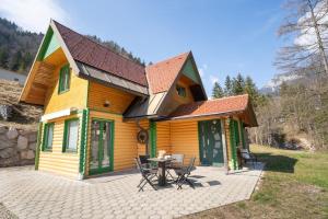 una casa con una mesa y sillas frente a ella en Butterfly Cottage by the Creek en Tržič