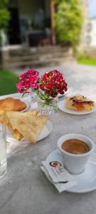 una mesa con una taza de café y un jarrón de flores en Guest-Room Zoi&Teri, en Tepelenë