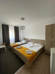 Un dormitorio con 2 camas y una silla. en Vila Mirela, en Eforie Nord