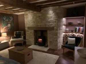 a living room with a stone fireplace and a chair at Beautiful grade 2 listed cotswold Stone Cottage in Chipping Norton