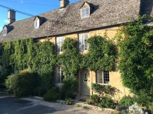 an ivy covered house with a white door at Beautiful grade 2 listed cotswold Stone Cottage in Chipping Norton