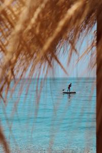 a person on a surfboard in the water at Rapos Resort Hotel in Himare