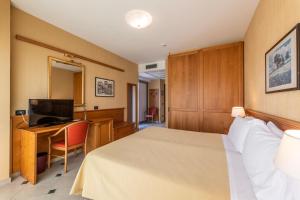 a hotel room with a bed and a desk with a television at Hotel Bellevue Et Mediterranée in Diano Marina