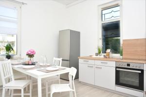 uma cozinha branca com uma mesa e cadeiras brancas em CO03-HI Apartment in Coburg em Coburgo